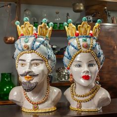 two ceramic busturines with crowns on top of each other in front of a shelf