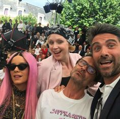 three people are posing for a photo in front of a group of people with pink hair