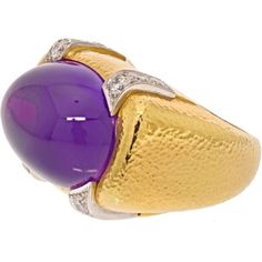 Captivating and alluring, the David Webb Platinum & 18K Yellow Gold Cabochon Amethyst And Diamond Cocktail Ring is a true masterpiece that will captivate your senses. This exquisite ring showcases a large cabochon amethyst, elegantly mounted in an East to West orientation, held securely by a sleek bezel. The deep, vibrant purple hue of the amethyst exudes an air of mystique and sophistication.Adding to its allure, this ring features round cut diamonds delicately placed in the four corners, creat Luxury Yellow Gold Oval Cabochon Gemstones, Luxury Formal Cabochon Amethyst Ring, Luxury Formal Amethyst Cabochon Ring, Luxury Amethyst Cabochon Ring For Formal Occasions, Luxury Yellow Gold Amethyst Ring Oval Cabochon, Luxury Round Cabochon Amethyst Ring, Luxury Purple Cabochon Amethyst Ring, Luxury Purple Amethyst Cabochon Ring, Luxury Yellow Gold Gemstone Cabochon