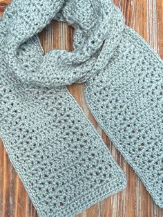 a gray crocheted scarf sitting on top of a wooden table