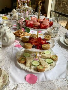 three tiered trays filled with pastries and cucumbers on a table