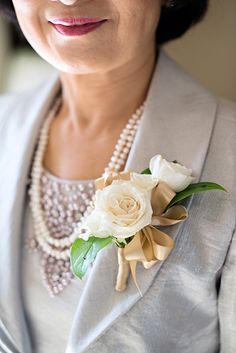 an older woman wearing pearls and a flower brooch