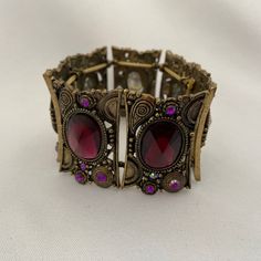 "This vintage brass and amethyst glass bracelet has an oriental flair. It consists of 7 elements strung together by strong rubber stretch bands. It is expandable.  Dimensions Approx. 2.36\" (6 cm) diameter x 1.57\" (4 cm) H. The width of each individual element is approx. 2\" (5 cm). The bracelet is in very good used condition." Adjustable Bohemian Bracelet With Antique Finish, Bohemian Metal Bracelets With Antique Finish, Bohemian Metal Bracelet With Antique Finish, Bohemian Antique Gold Adjustable Bracelets, Ornate Adjustable Brass Bracelet, Bohemian Adjustable Jeweled Bracelet, Vintage Purple Jewelry For Festival, Bohemian Bronze Bracelets With Antique Finish, Bohemian Bronze Bracelet With Antique Finish