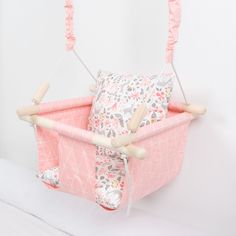 a pink baby swing hanging from the side of a white wall with flowers on it