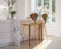 two wooden chairs sitting next to each other in front of a marble counter top island