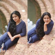 a woman sitting on top of a stone wall next to water