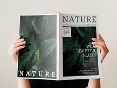 a person holding up a magazine with green leaves on it