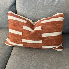 an orange and white pillow sitting on top of a gray couch