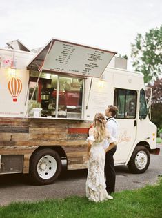 a man and woman standing in front of a food truck