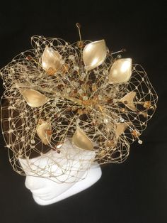 Delicate gold fascinator perfect for the guest who wants something fairly understated. This design is a beautiful selection of glass effect leaves and flowers with an additional scatter of brown crystal and tan glacier stone, clustered together amongst a fine layer of veiling and set onto a fine comfort base tiara band. As with all our designs, this piece can be made exact to the image or in any colour combination to match in with your outfit. If a specific colour is required customers can messa Handmade Gold Headpiece With Pinched Crown, Handmade Gold Hair Accessories For Wedding, Elegant Headband Fascinator As Gift, Elegant Gold Fascinator As Gift, Gold Wedding Crown Hair Accessory, Gold Crown Hair Accessories For Wedding, Elegant Gold Headpieces For Gift, Elegant Gold Headpieces As Gift, Handmade Gold Hats For Party