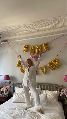 a woman standing on top of a bed holding onto some red streamers that say same love