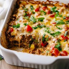 a casserole dish with meat, cheese and vegetables in it on a wooden table