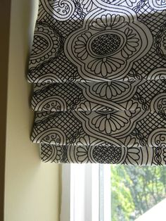 a window with a black and white patterned blind in front of a window sill