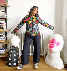 a woman is standing in front of some art sculptures and bookshelves with her arms outstretched