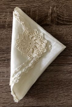 a white napkin with lace on it sitting on top of a wooden table