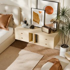 a white bed sitting next to a wooden dresser in a room with two framed pictures on the wall