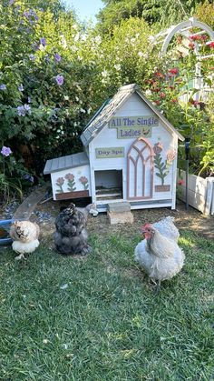 three chickens sitting in front of a small chicken house