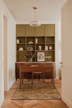 a room with a desk, bookshelf and chair in it's center