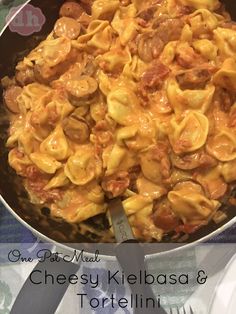 a skillet filled with pasta and meat on top of a table next to silverware