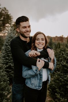 a man and woman hugging in front of christmas trees