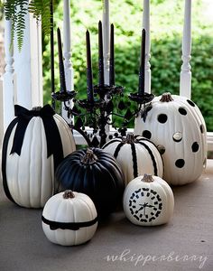 white pumpkins with black bows and candles are on the front porch for halloween decor