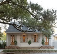 a small white house sitting next to a tree