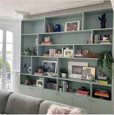 a living room filled with lots of bookshelves next to a couch and window