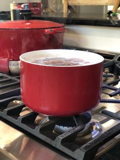 two red pots sitting on top of a stove next to each other in front of an oven