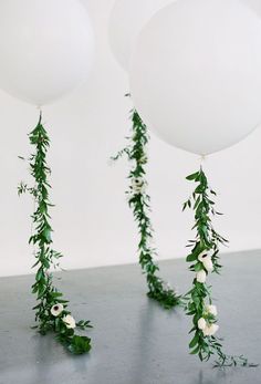 two balloons with flowers and greenery hanging from them