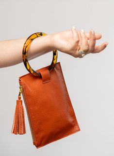 This bag is made from high-quality, super-soft spice leather sourced from a premiere hide house in California. The leather is shipped to New York City, where our bags are produced by expert craftsmen and finished with a smooth zipper, leather tassel, and acrylic ring. Just big enough for all your essentials, we designed the Ring Wristlet to be your go-to bag for going out! Whether you’re heading to a cocktail party, a concert, or out on the town, slip it on your wrist so your hands are free for Handheld Leather Clutch For On-the-go, Leather Handheld Clutch For On-the-go, Leather Pouch With Zipper Closure, Handheld Leather Pouch With Zipper Closure, Modern Handheld Leather Pouch, Leather Clutch With Detachable Round Handle, Versatile Leather Clutch With Smooth Grain, Handheld Soft Leather Clutch, Leather Handheld Pouch With Detachable Strap