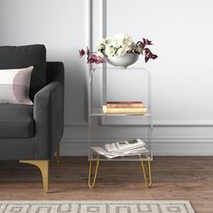 a living room with a gray couch and white flowers in a vase on a glass shelf