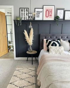 a bed room with a neatly made bed and lots of pictures on the wall above it