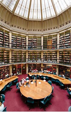 a large library filled with lots of books and people sitting at tables in front of them