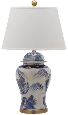 a blue and white porcelain lamp with a gold base on a white table cloth shade