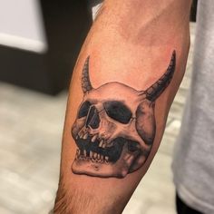 a man's arm with a skull and horns tattoo on it