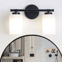 a bathroom mirror that has two lights on top of it and a sink in the background