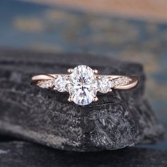 a three stone diamond ring on top of a rock