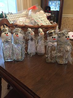 several glass jars with snowmen in them on a table next to a basket and keyboard