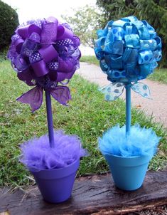 two flower pots with purple and blue flowers in them sitting on a tree stump next to each other