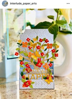 a close up of a greeting card on a table with a vase in the background