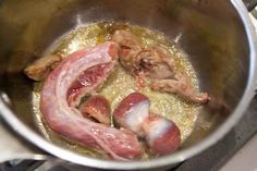 two sausages are cooking in a pot on the stove top, with other ingredients