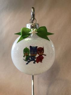 a glass ornament with two cartoon characters on it and a green bow around the neck