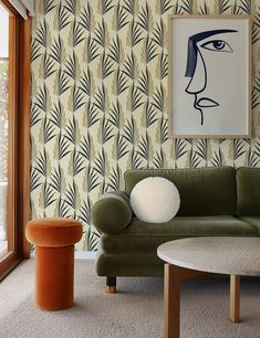 a living room with green couches and wallpaper