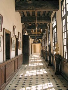 a long hallway with chandeliers and pictures on the wall in an old building