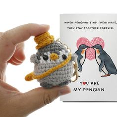 a hand holding a tiny crocheted penguin with a hat on it's head