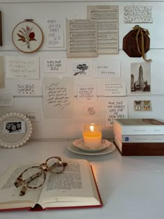 an open book sitting on top of a table next to a candle and some pictures