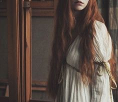 a woman with long red hair wearing a white dress