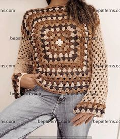 a woman wearing a crocheted sweater and jeans posing for the camera with her hands on her hips