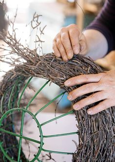 someone is working on a wreath made out of twigs