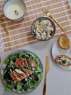 a table topped with plates of food next to bowls of sauces and utensils